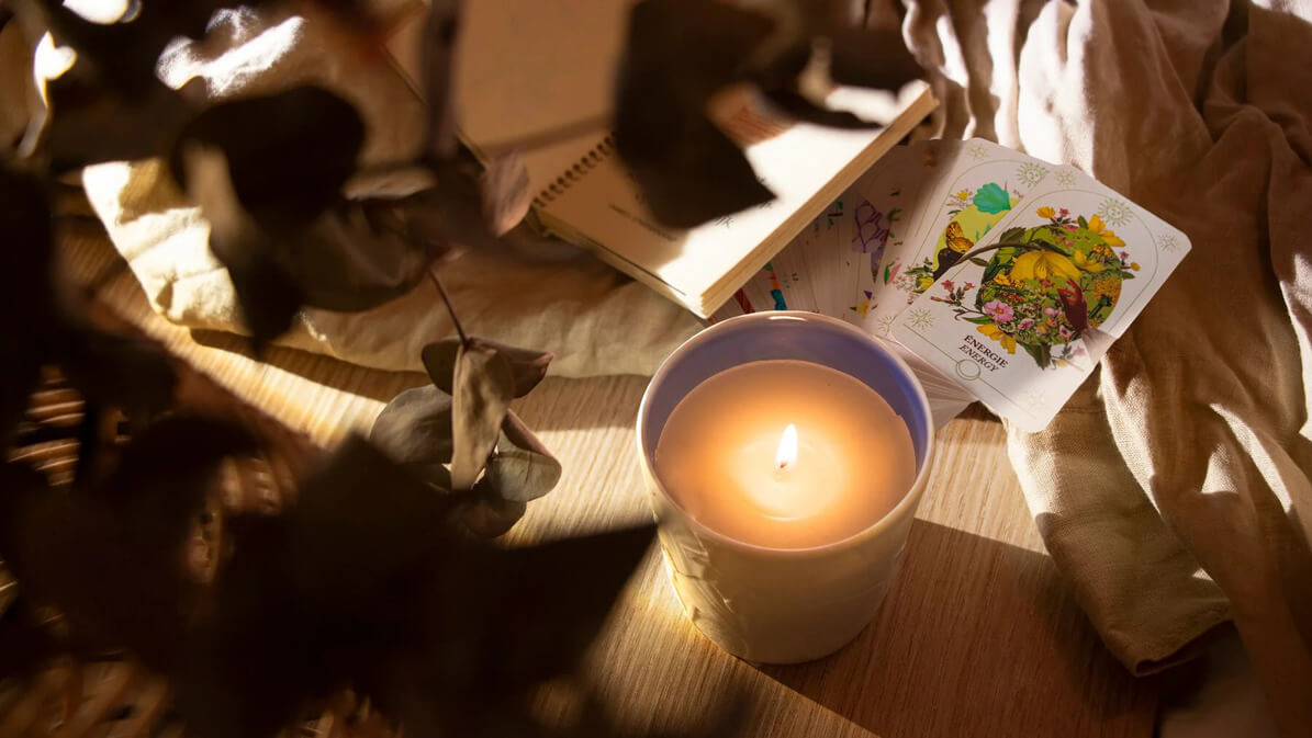 Une bougie  et cahier et les carte de L'oracle du Jardin Retrouvé  sur une table